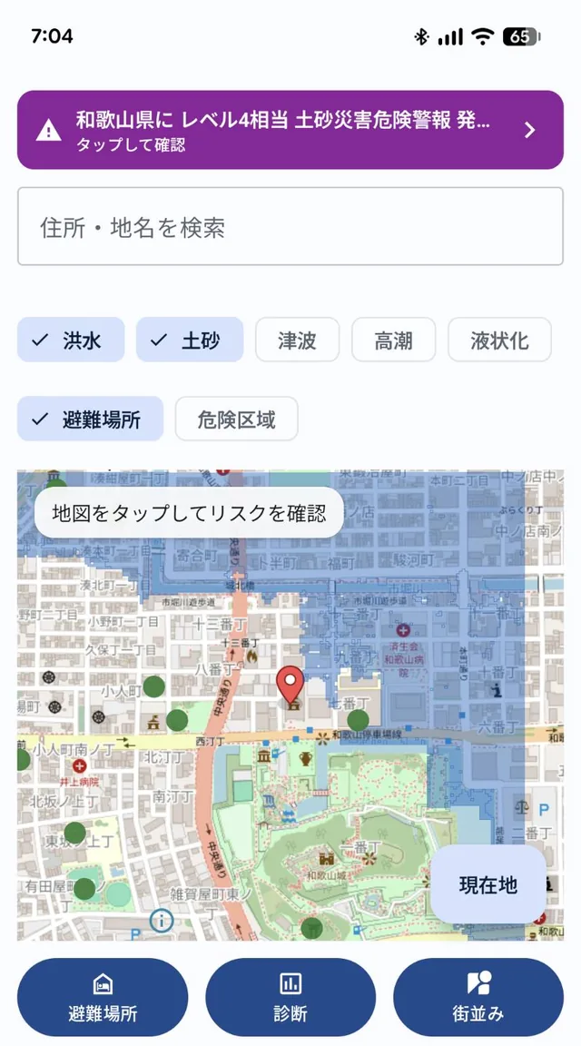 地図画面。住所・地名の検索欄と、洪水・土砂・津波・高潮・液状化・避難場所・危険区域のレイヤー切替ボタンがあり、地図上にハザード情報と避難場所のマーカーが重ねて表示されている。上部には発表中の土砂災害危険警報のバナー